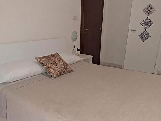 Camera matrimoniale con letto rifatto e porta decorata a cementine