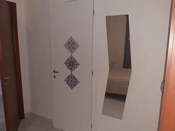 Porta della camera decorata con piastrelle a rombo e specchio a figura intera